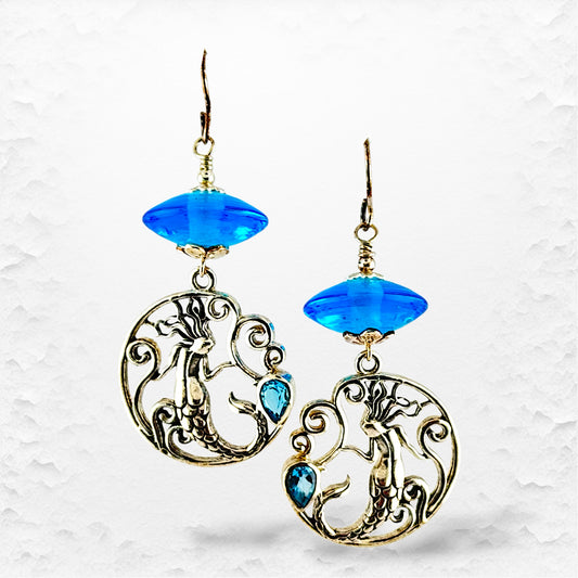 Pair of earrings with blue gemstones on a textured white background