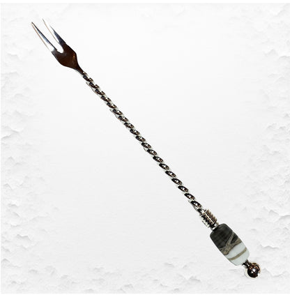 Decorative hairpin with chain and beads on a textured white background