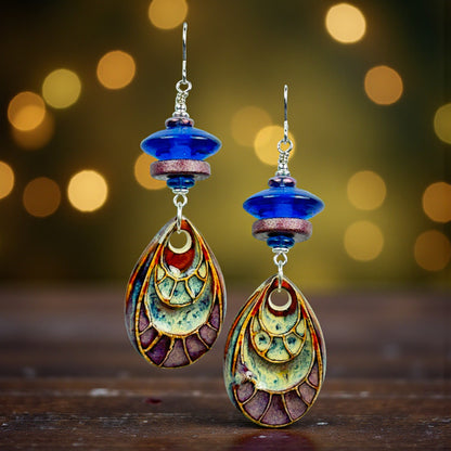 Colorful earrings with intricate designs on a wooden surface and blurred lights background