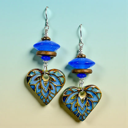 Heart-shaped earrings with blue and gold design on a gradient background