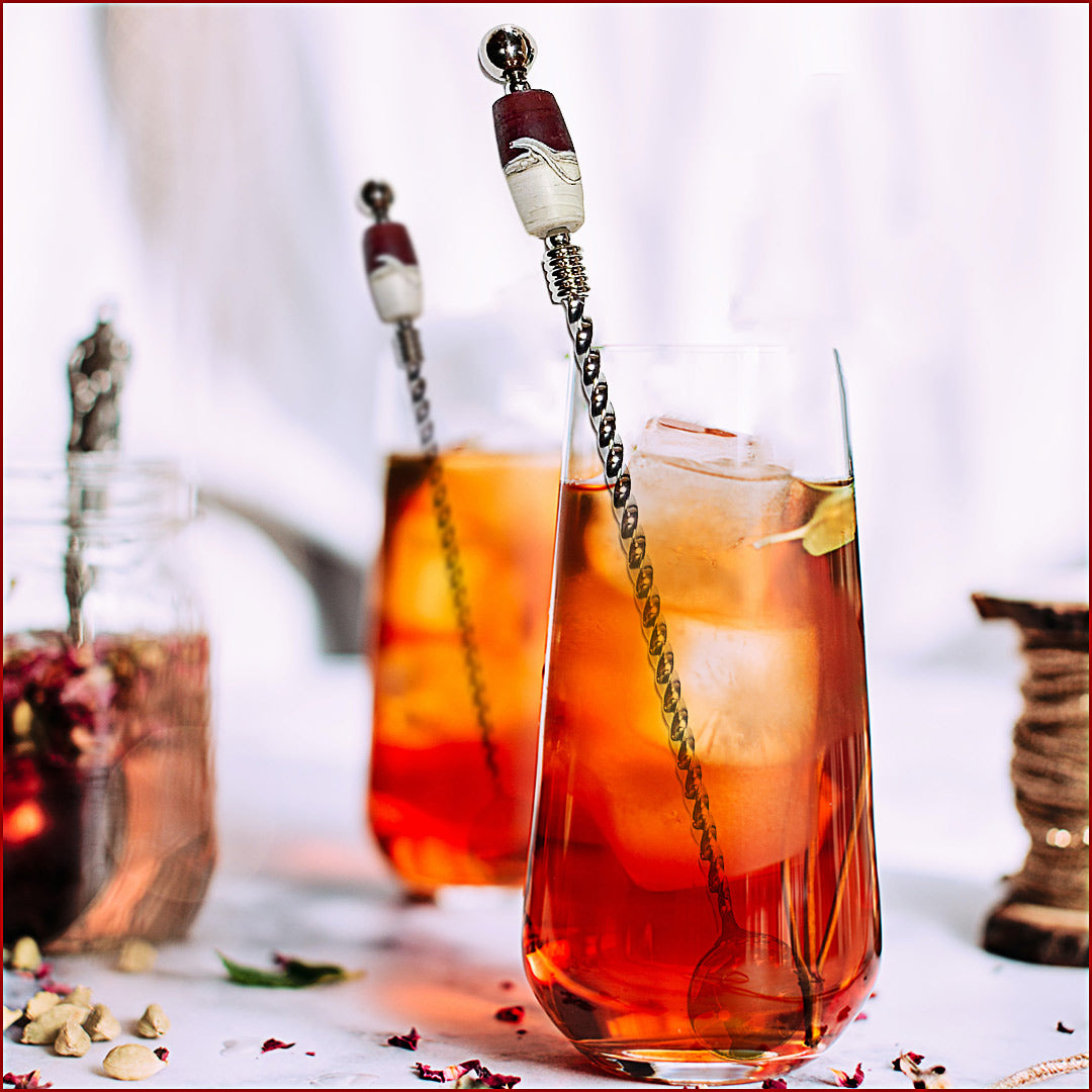Two glasses of iced tea with lemon slices and decorative straws on a white surface.