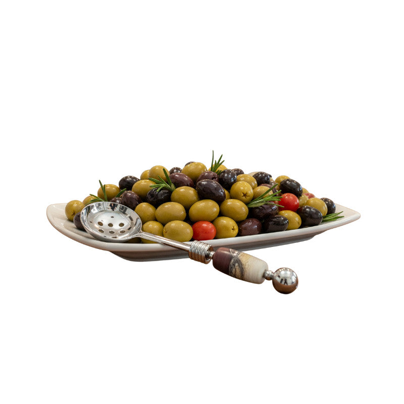 Decorative platter with assorted olives and a serving spoon on a white background