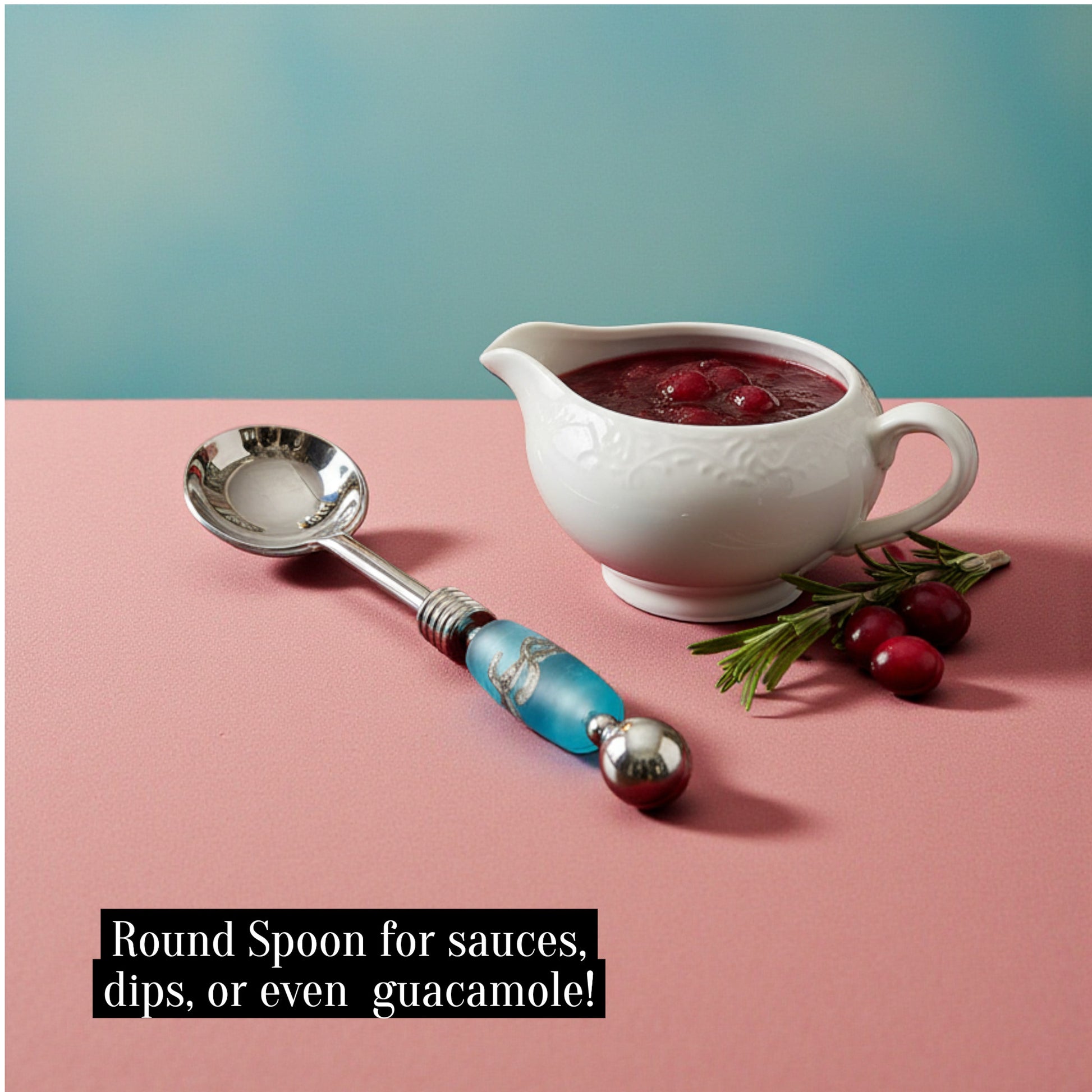 White sauceboat with red sauce, a decorative spoon, and cranberries on a pink surface with a teal background.