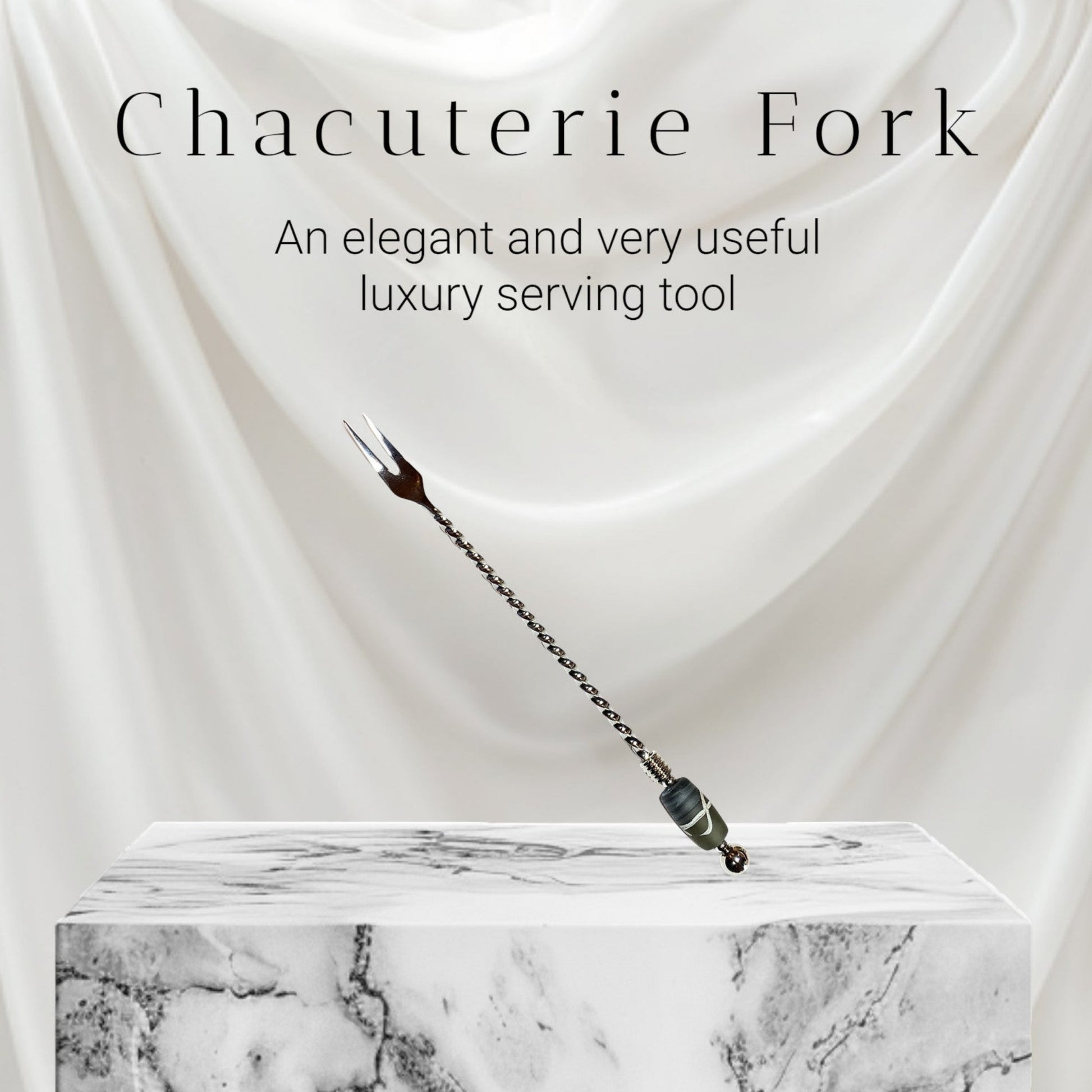 Chacuterie fork on a marble platform with white fabric background
