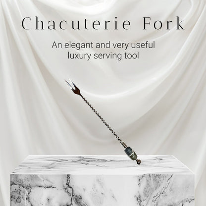 Chacuterie fork on a marble platform with white fabric background